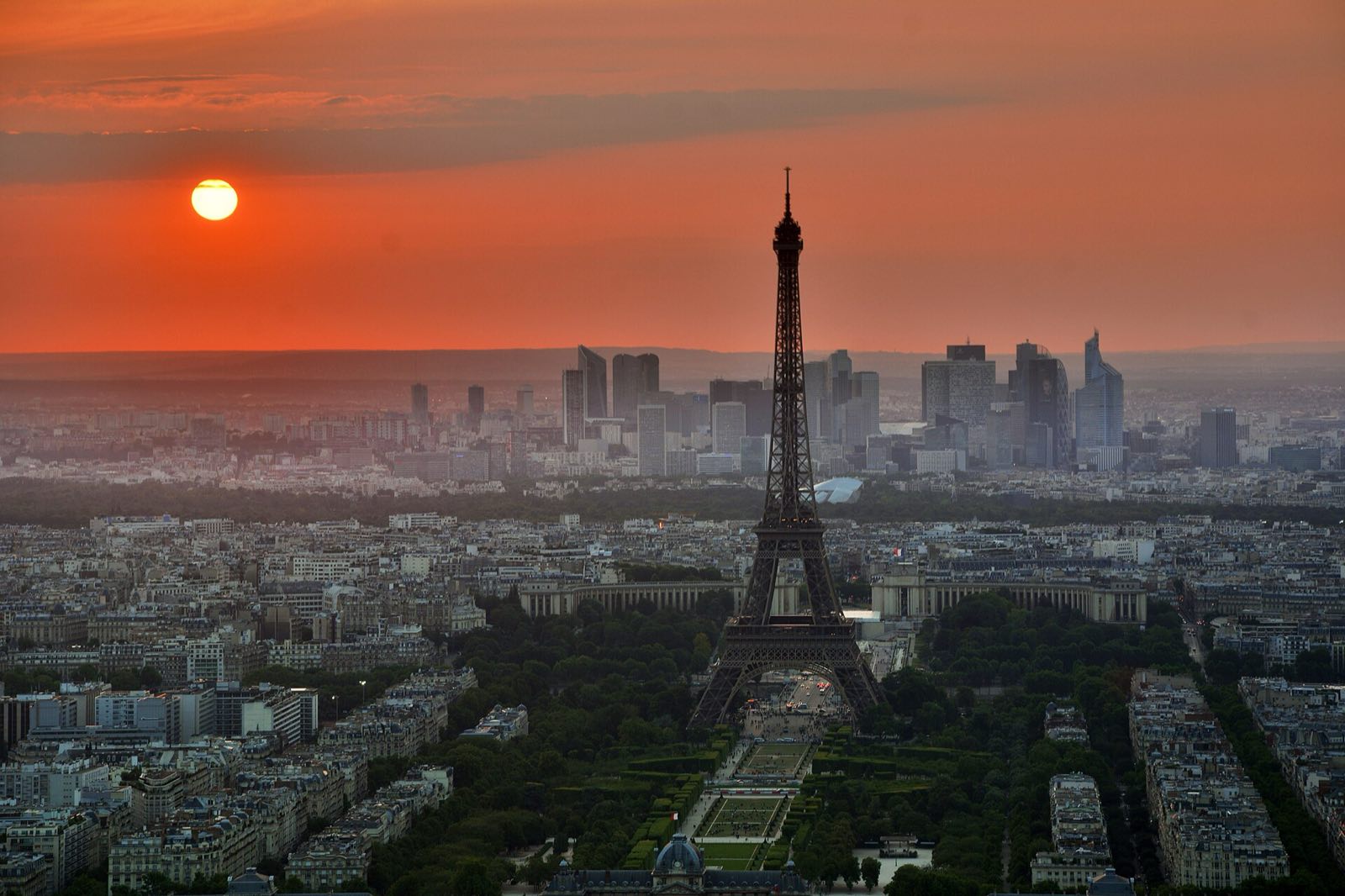 The Eiffel Tower above the rooftops of Paris at sunset.