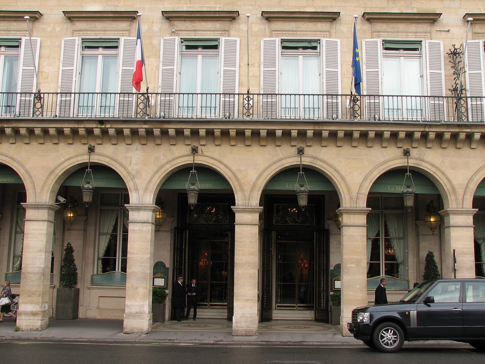 The entrance of Le Meurice under the arcades of the rue de Rivoli, with flags above the arches.