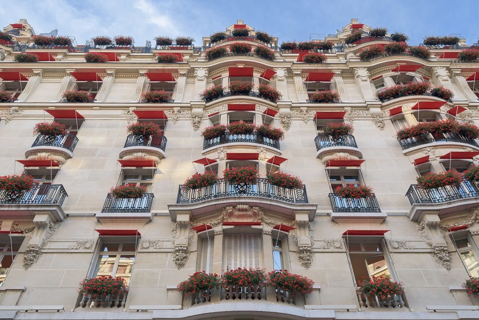 The front of the Hôtel Plaza Athénée, every balcony hung with red awnings and red geraniums.