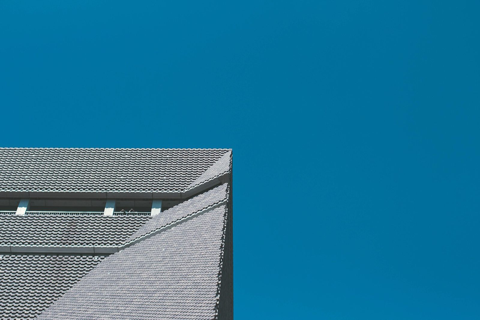 A corner of the brick tower of Tate Modern against a blue sky.